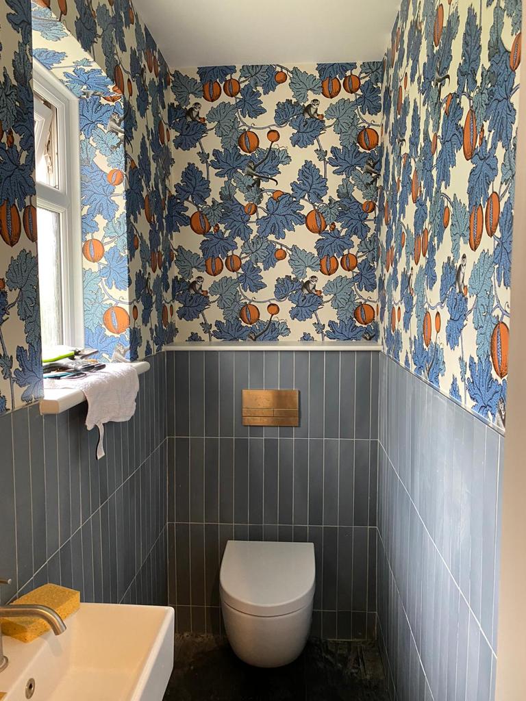 Small bathroom with bold blue and orange floral wallpaper and a modern white toilet.