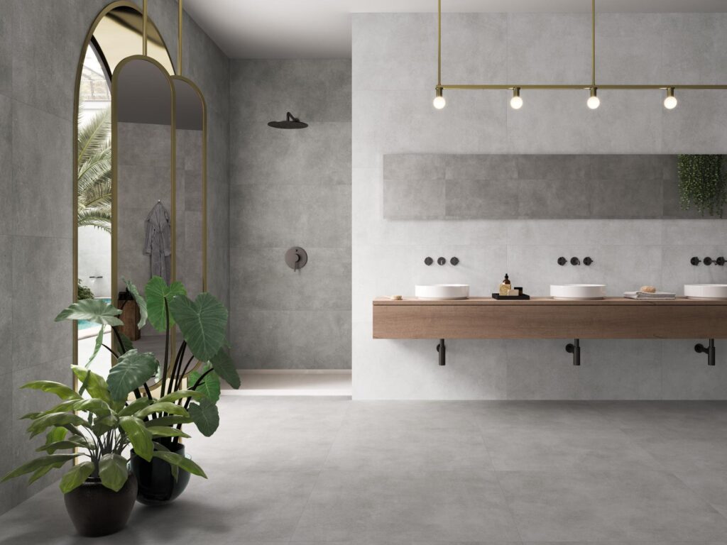 pam1900x2129-4b45426d-1920w.jpg Modern bathroom with gray walls, large mirror, double sinks, and potted plants near a tall arched window.