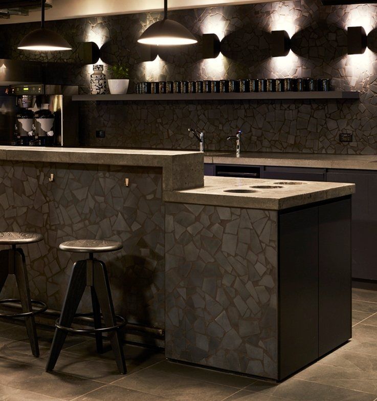 Modern kitchen with terrazzo tile surfaces, bar stools, and pendant lighting.