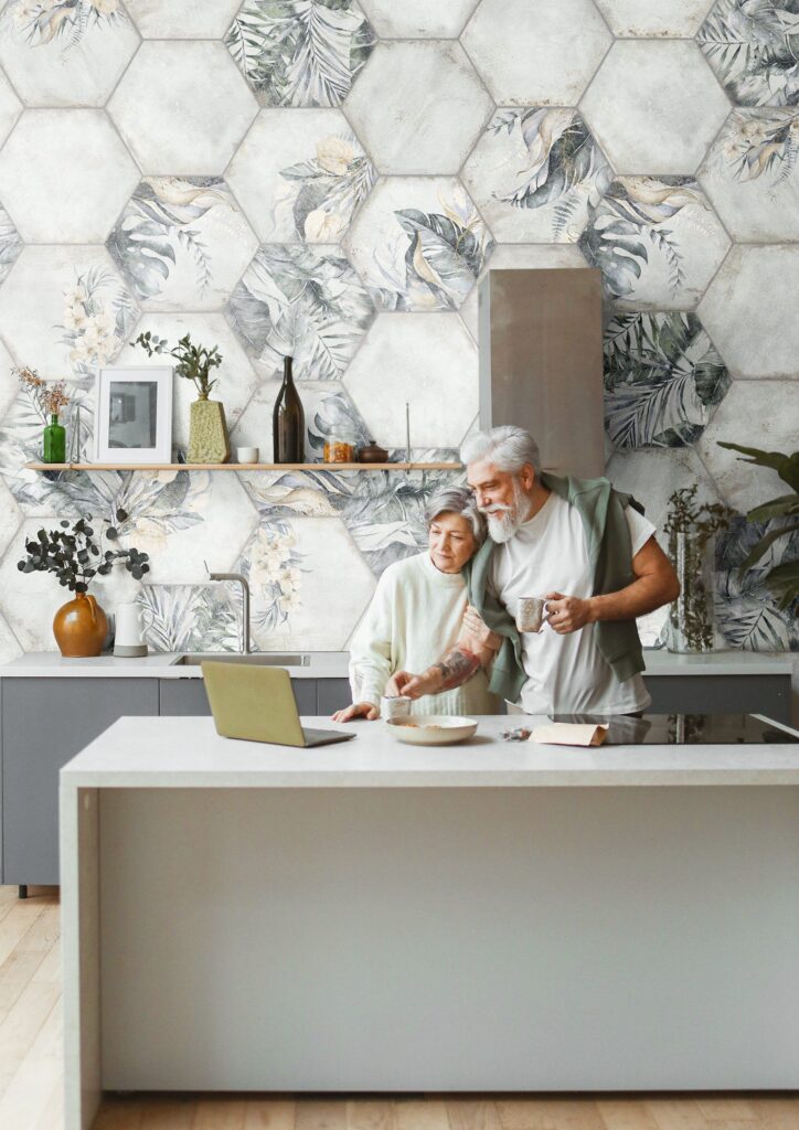 Older couple cooking together in a modern kitchen with hexagon tile wall and open shelves.