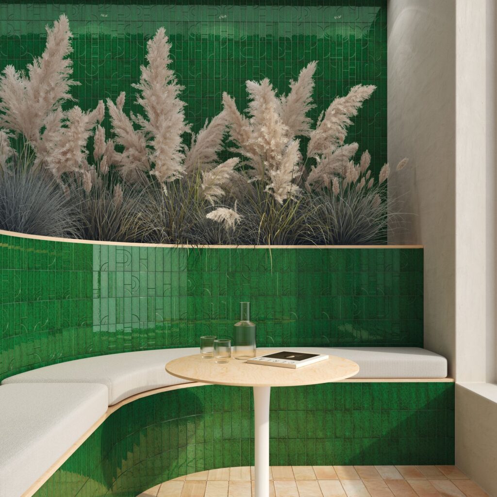 Curved white bench and round table with green tiled wall and decorative grasses in the background.