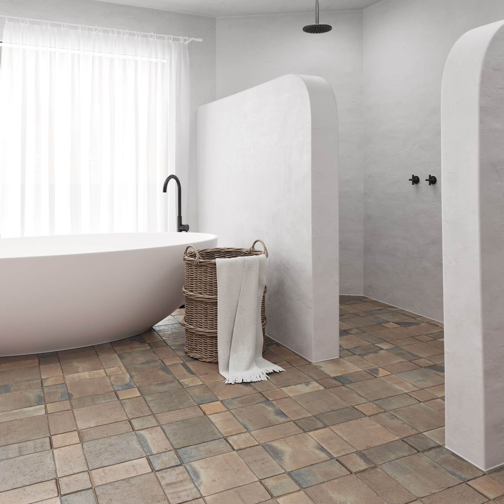 Modern bathroom with a freestanding tub, woven basket, and rustic tiled floor.