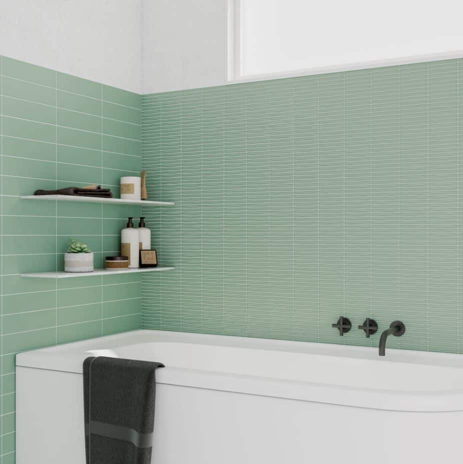 stix+sage+matt-1920w.JPG Modern bathroom with green wall tiles, white bathtub, two shelves, and black faucet fixtures.