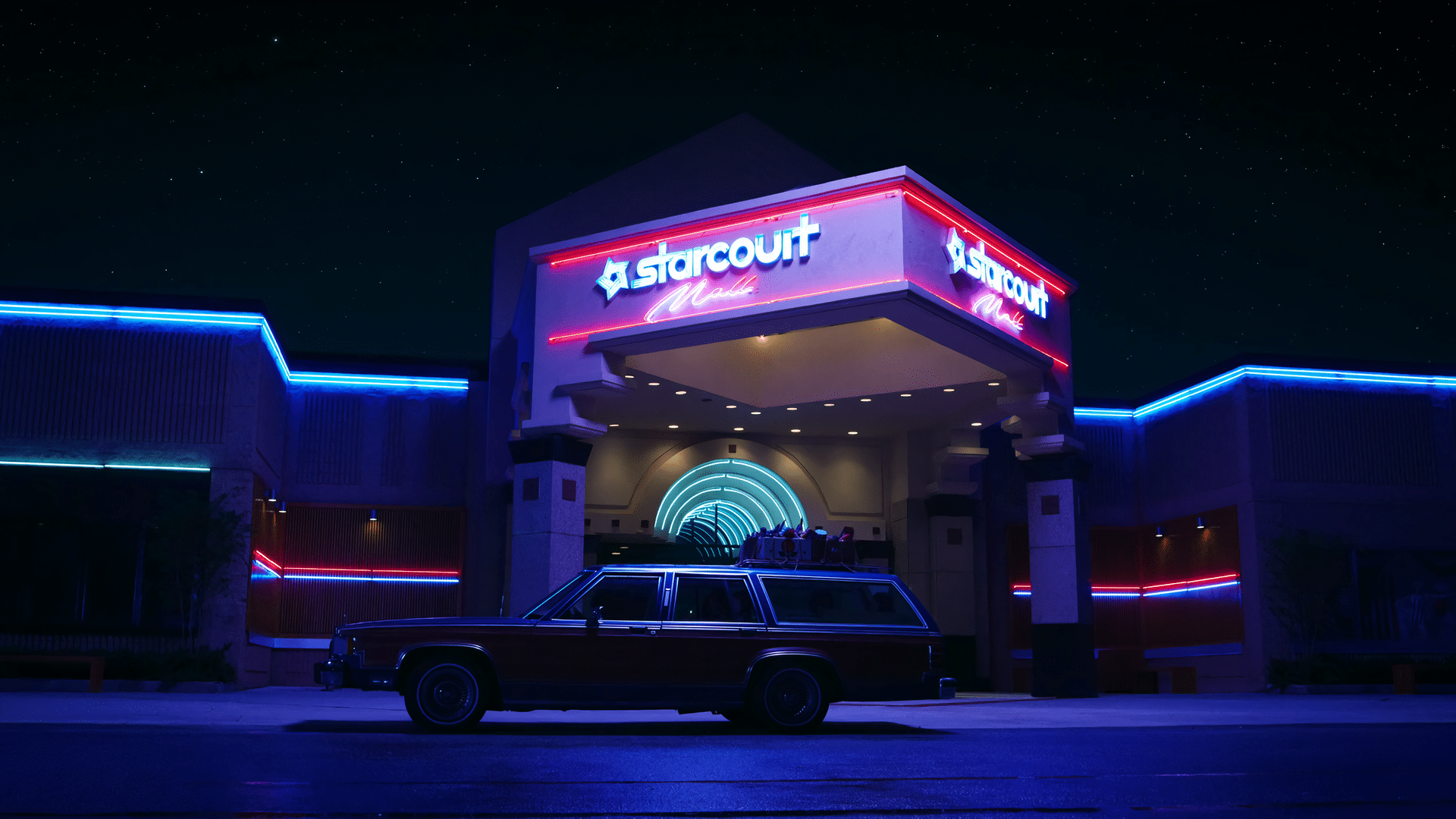 Exterior shot of Starcourt mall from stranger things after dark. 1980's station wagon sits outside.