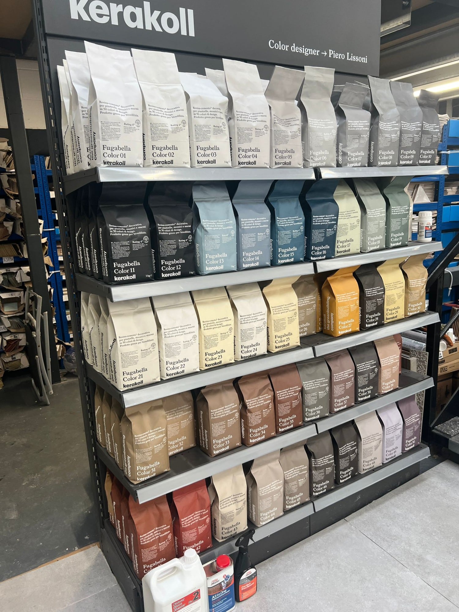 Bags of Kerakoll grout in various colors displayed on shelves in a store.
