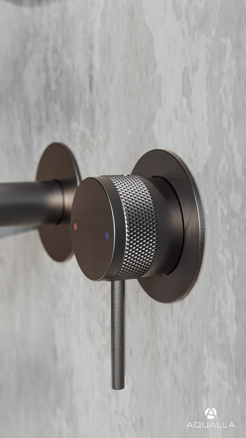 Close-up of a modern shower dial with a textured grip, mounted on a tiled bathroom wall.