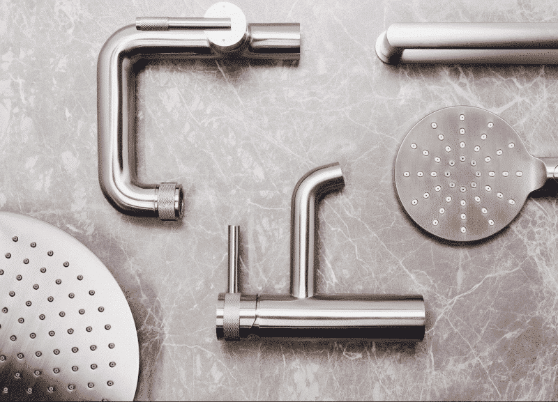 Silver faucets and shower heads arranged on a gray marble surface.