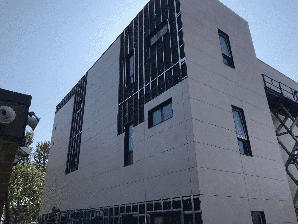 Modern building facade under construction with visible panels and windows.
