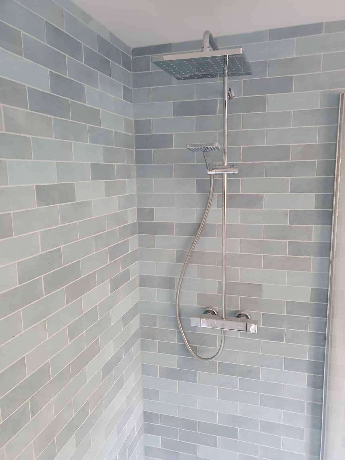 Modern shower with a square showerhead and gray subway tile walls.