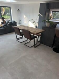 Modern dining area with a wooden table, chairs, and a nearby sofa in a bright room.