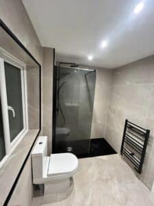 Modern bathroom with a toilet, walk-in shower, window, and wall-mounted towel rack.