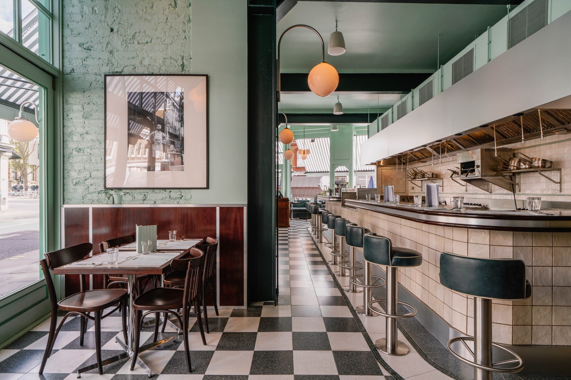Retro-style diner with checkered floor, bar stools, tables, and soft lighting near large windows.