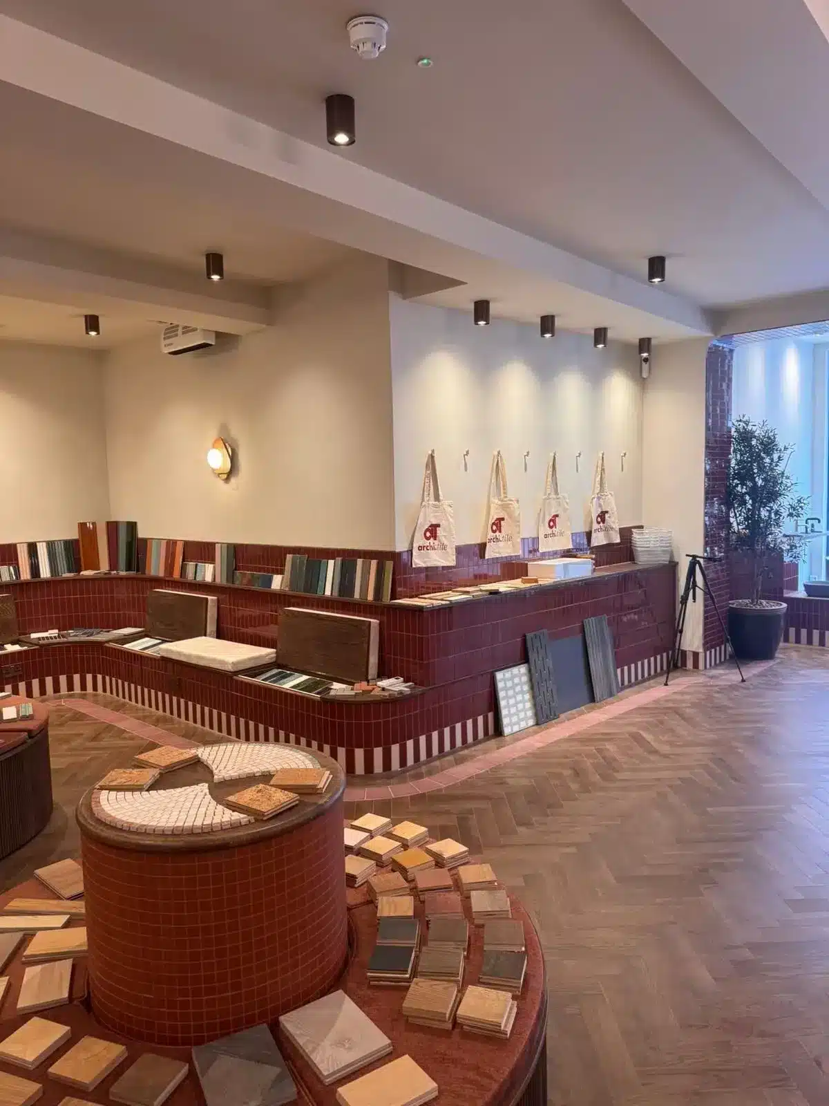 Showroom interior with sample tiles and wood pieces displayed on red tiled counters and wooden floors.