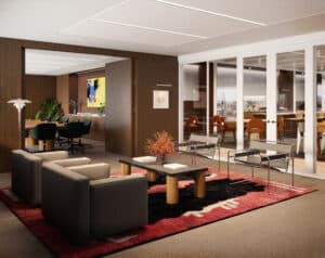 Modern office conversation room with sofas, chairs, and a coffee table on a red rug.