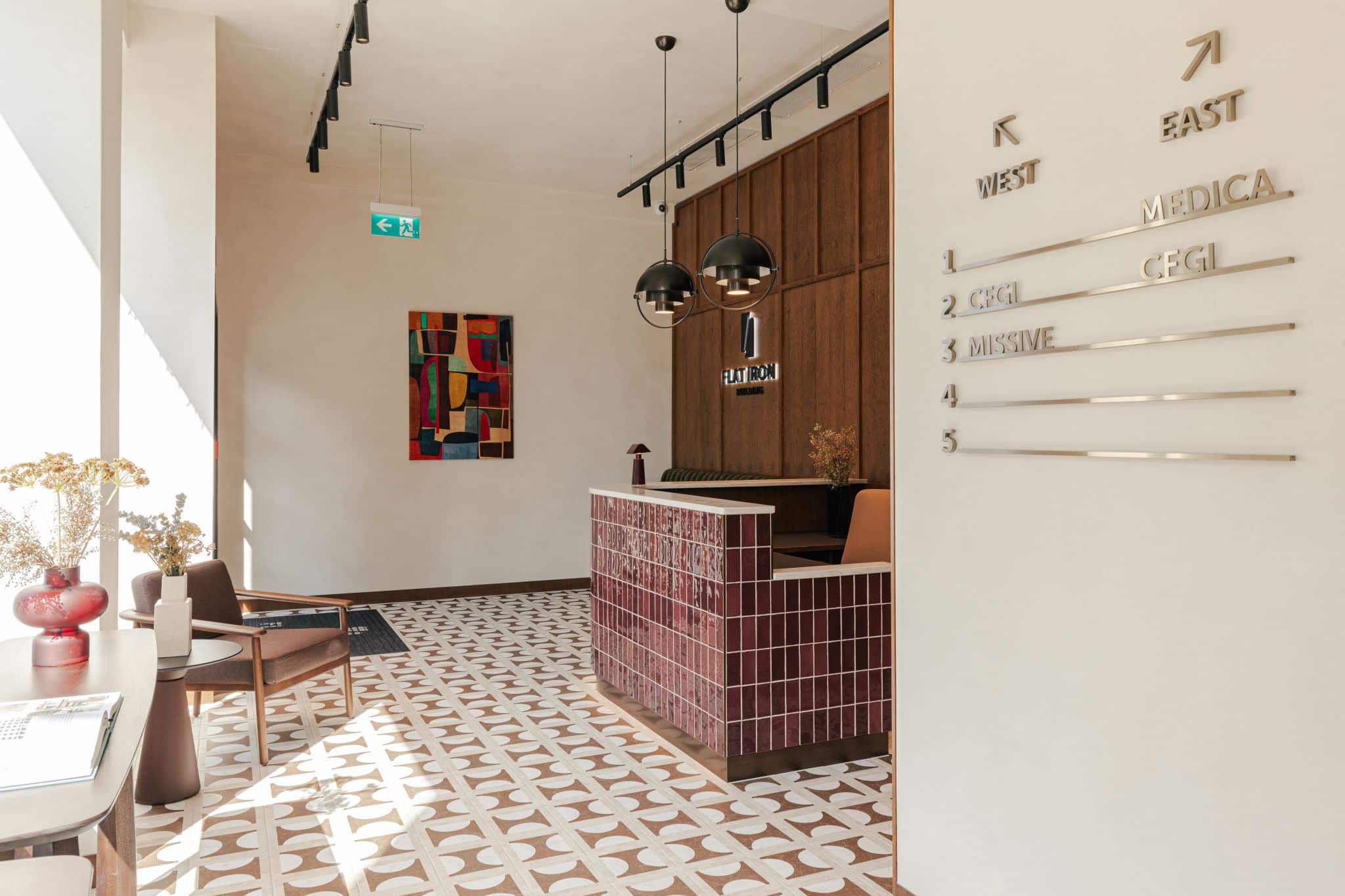 Modern lobby with geometric floor tiles, a tiled reception desk, and wall signage.