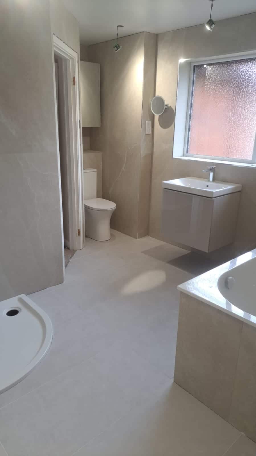 Modern bathroom with toilet, sink, shower, and bathtub in neutral colors.