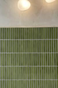Close-up of a green tiled kitchen splashback with thin white grout lines.