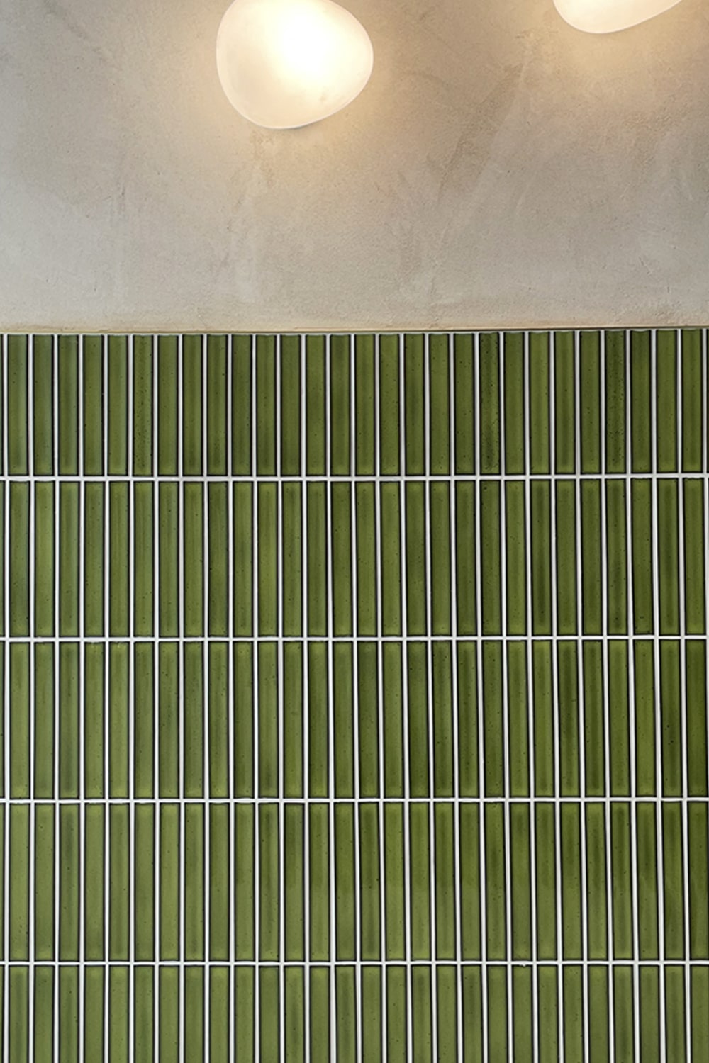 Close-up of a green tiled kitchen splashback with thin white grout lines.