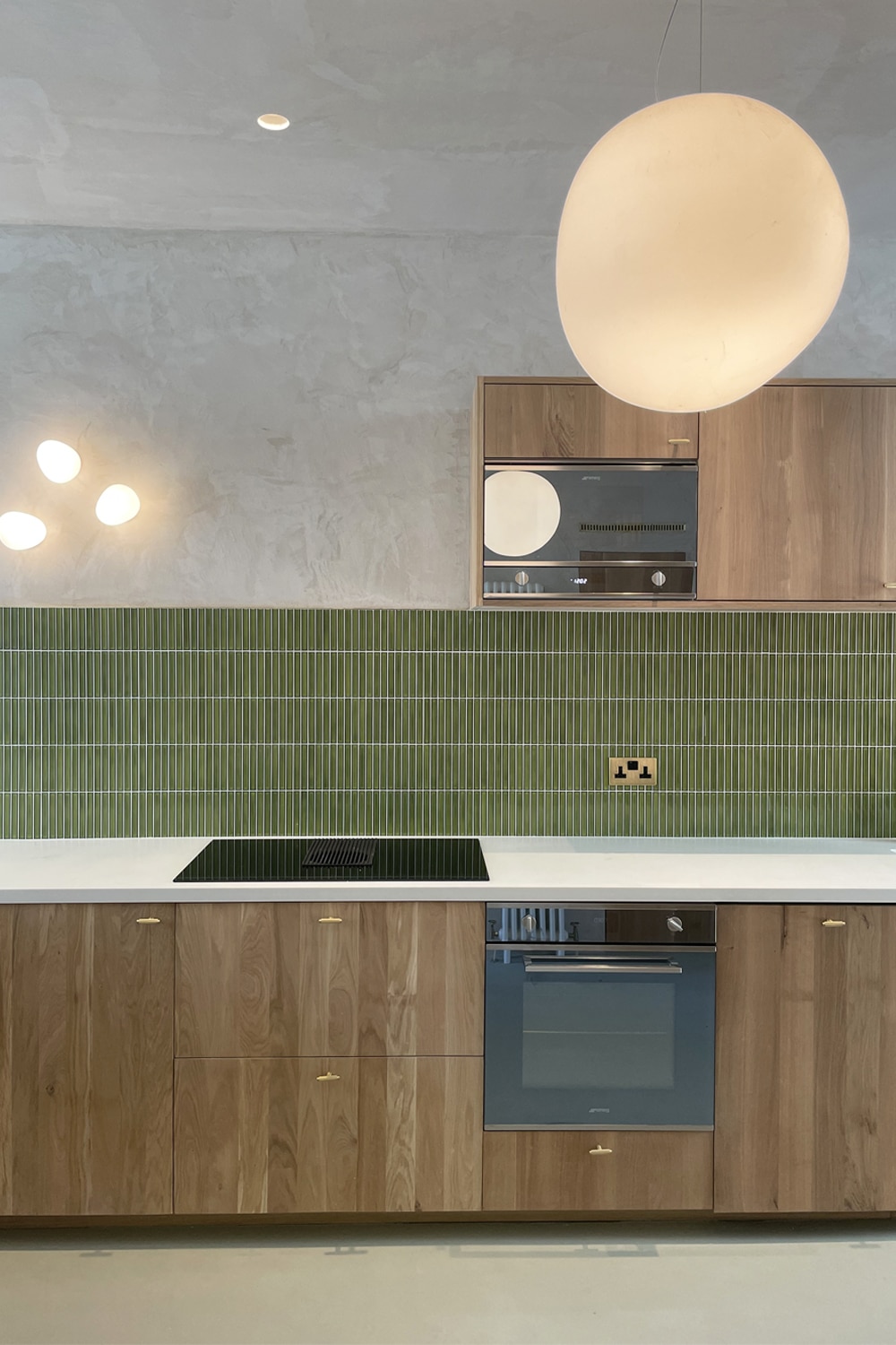 Modern kitchen with green tile backsplash, wooden cabinets, and built-in appliances.