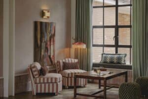 Cozy living room with striped chairs, a wooden table, and large window with curtains.