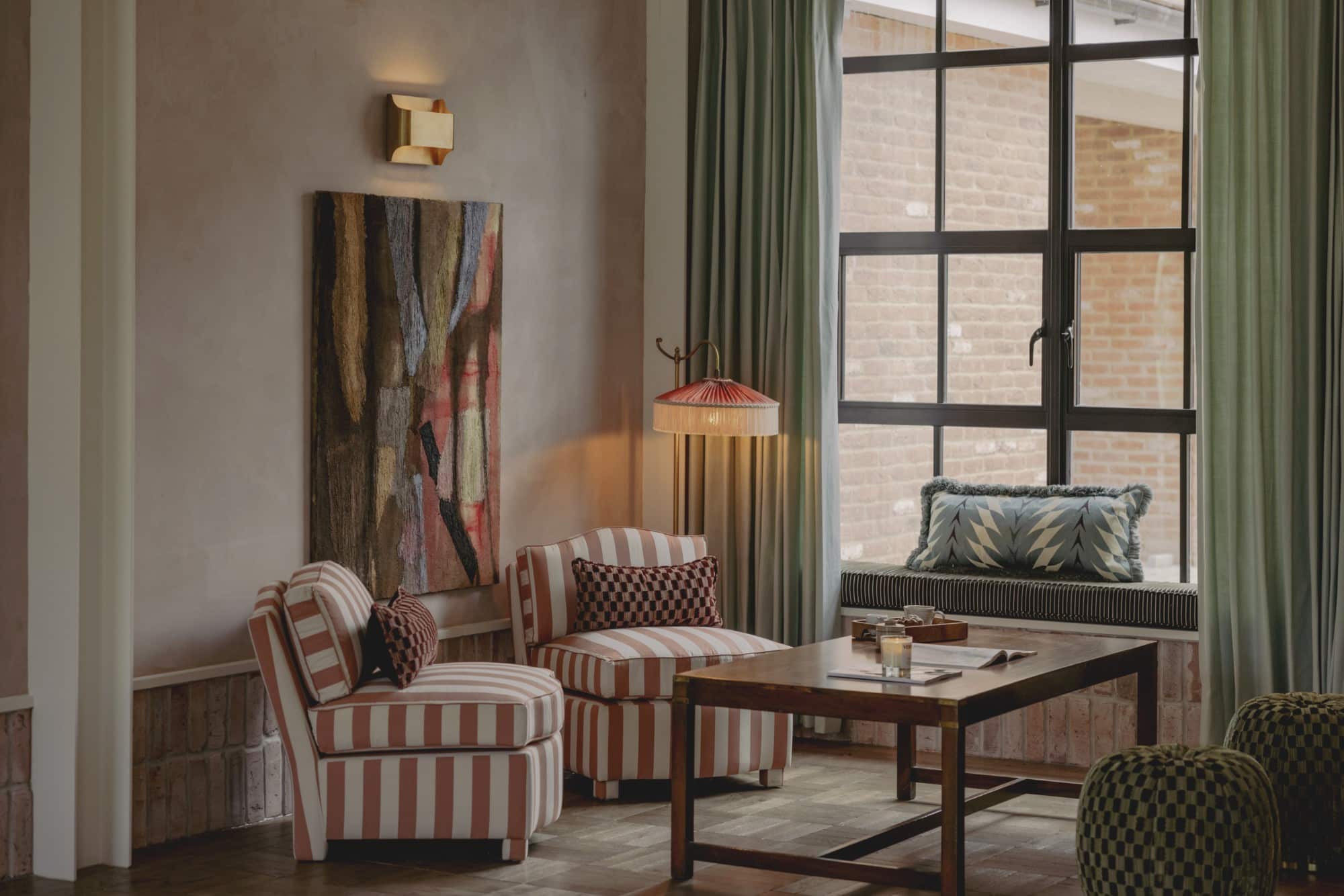 Cozy living room with striped chairs, a wooden table, and large window with curtains.
