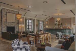 A cozy lounge with sofas, armchairs, a fireplace, and a bar in a warmly lit room.
