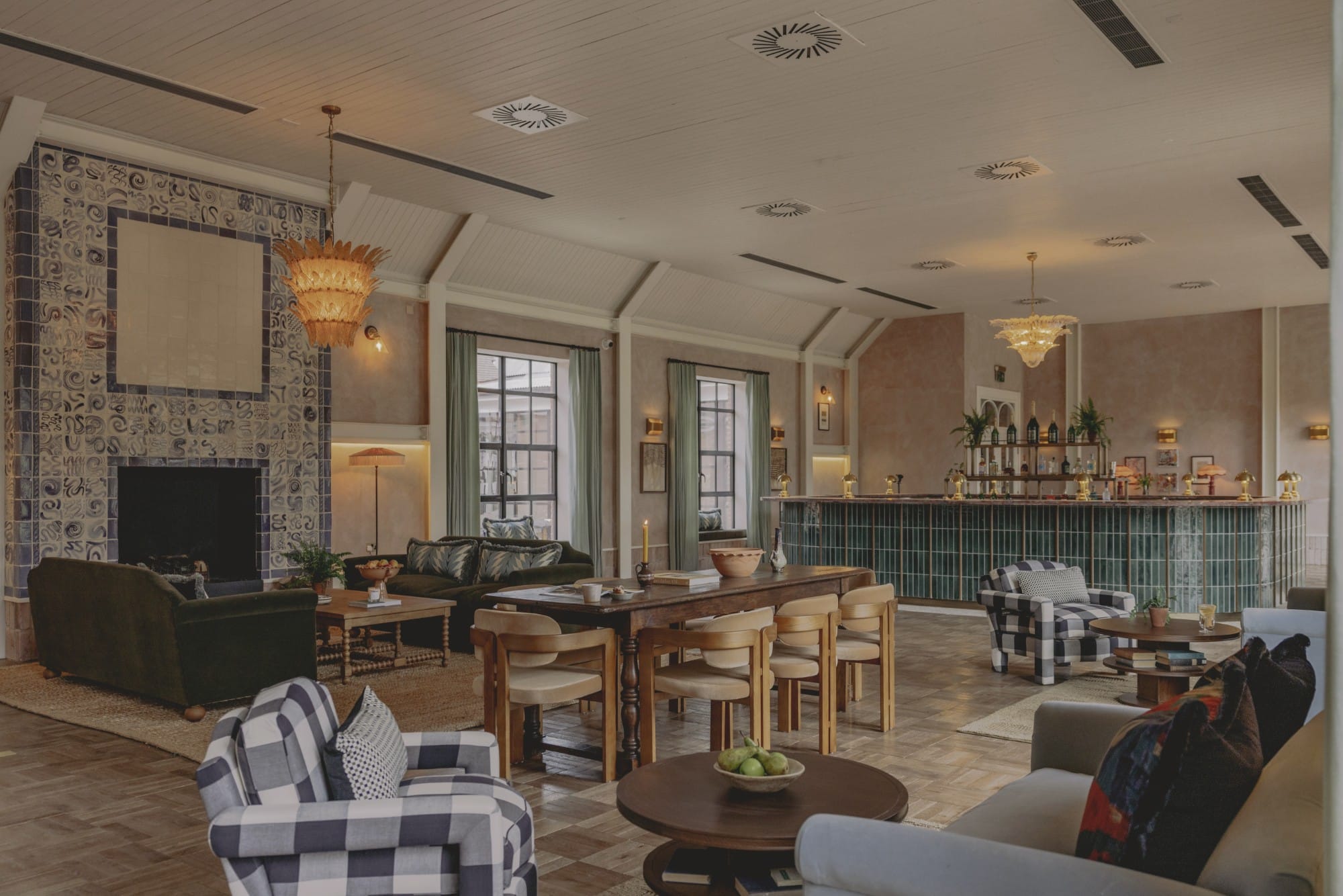 A cozy lounge with sofas, armchairs, a fireplace, and a bar in a warmly lit room.