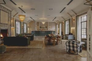 Elegant lounge with sofas, a fireplace, dining table, bar, and large windows letting in natural light.