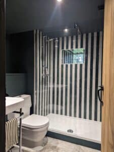 Modern bathroom with a walk-in shower and black and white vertical striped tiles.