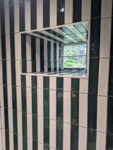 Green and white striped tiled wall with a window looking outside.