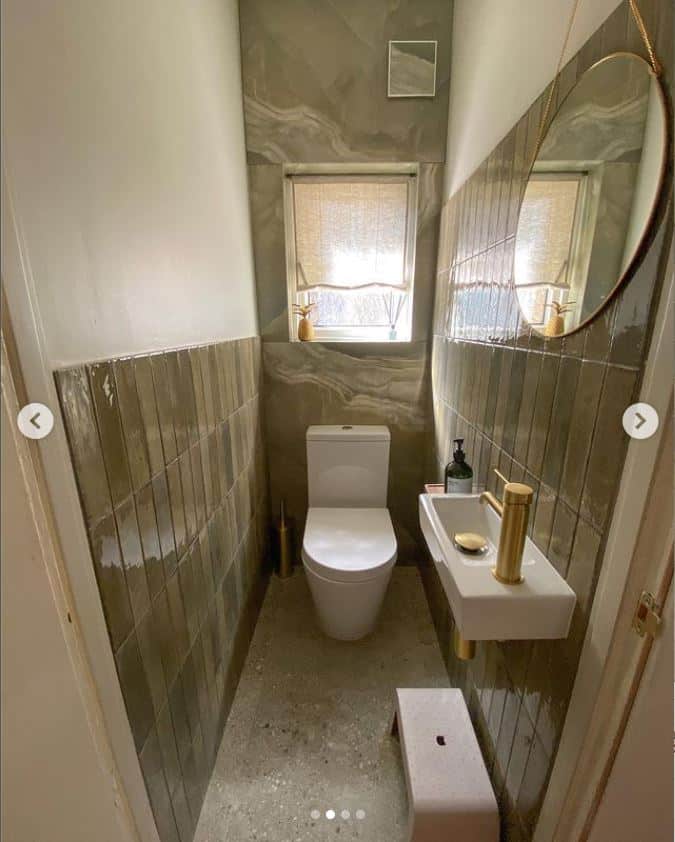 Small modern bathroom with a toilet, sink, mirror, and window.