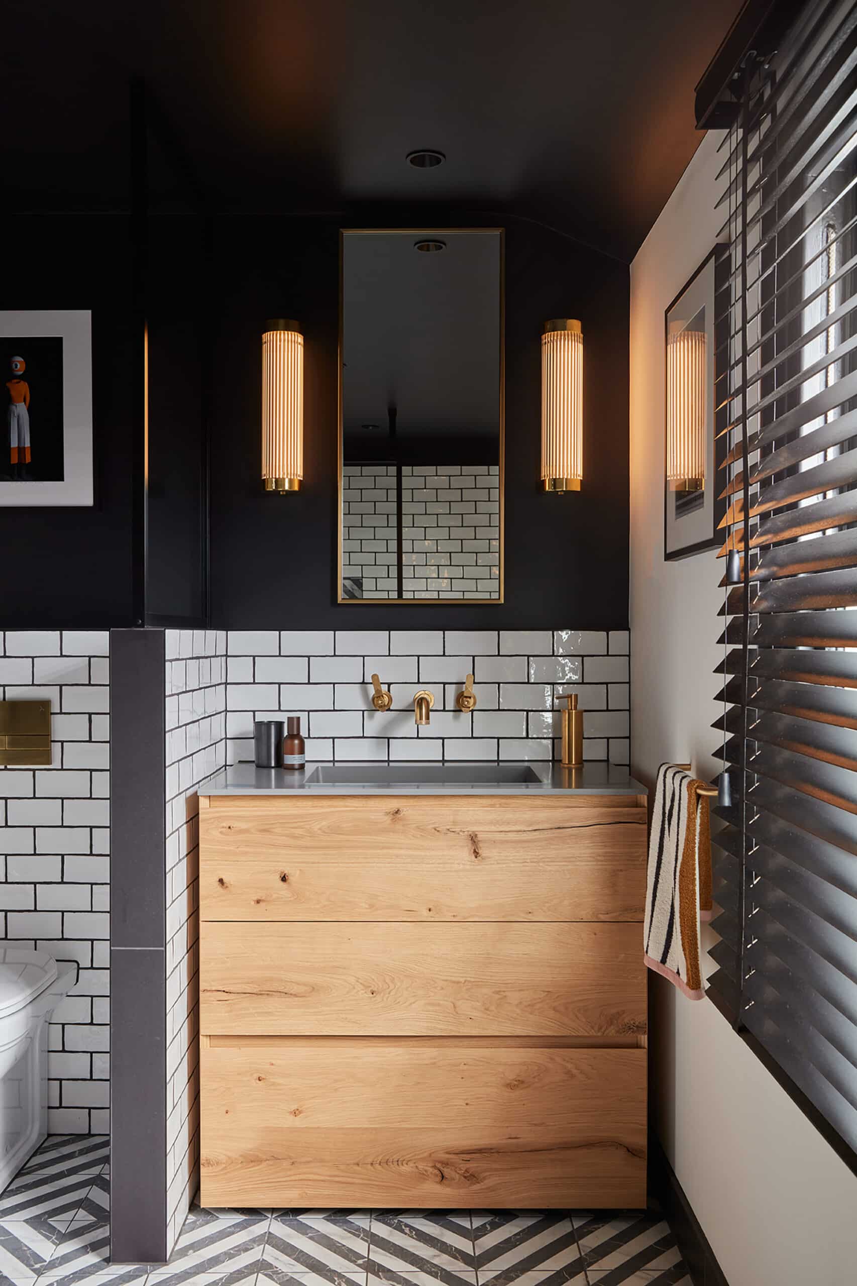 Modern bathroom with wood vanity, white subway tiles, and two wall lights beside a mirror.