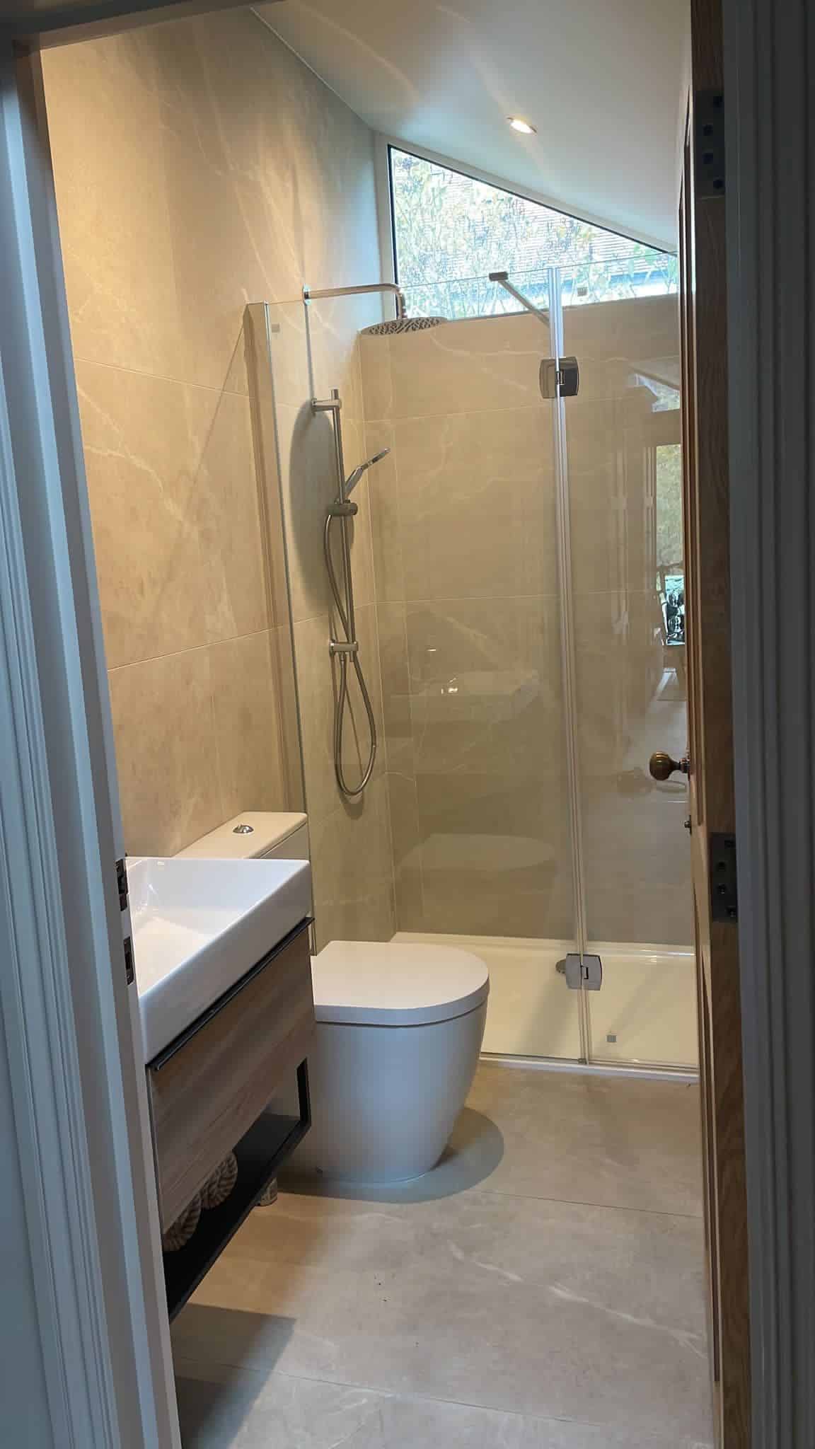 Modern bathroom with a toilet, sink, and glass shower enclosure.